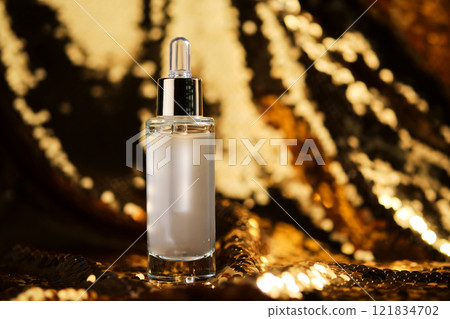A bottle of cosmetic serum with a pipette on a festive golden background. 121834702