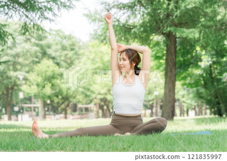 A female yoga instructor doing forest bathing, deep breathing, exercise, stretching, yoga and pilates in the park A female yoga instructor doing forest bathing, deep breathing, exercise, stretching, yoga and pilates in the park 121835997