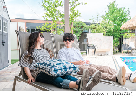 Couple sitting by the pool at a resort hotel on a trip 121837154
