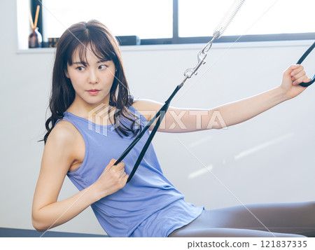 A woman taking a machine pilates lesson A woman taking a machine pilates lesson 121837335