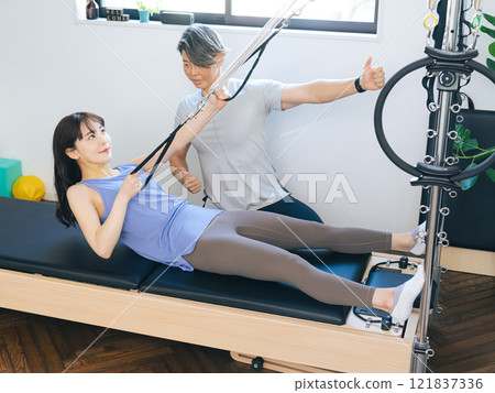 一位女士正在上機器普拉提課 一位女士正在上機器普拉提課 121837336