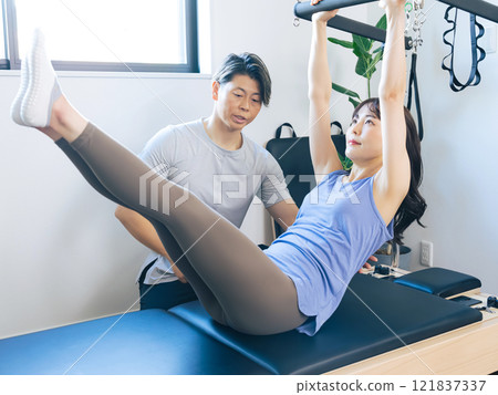 Woman doing machine pilates training Woman doing machine pilates training 121837337