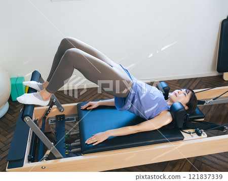 Woman doing machine pilates training Woman doing machine pilates training 121837339