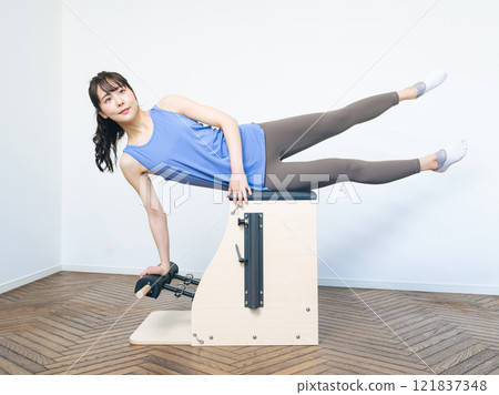 Woman doing machine pilates training Woman doing machine pilates training 121837348