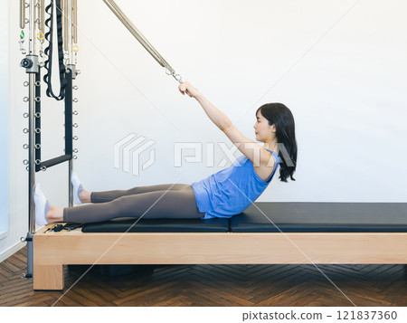 Woman doing machine pilates training Woman doing machine pilates training 121837360