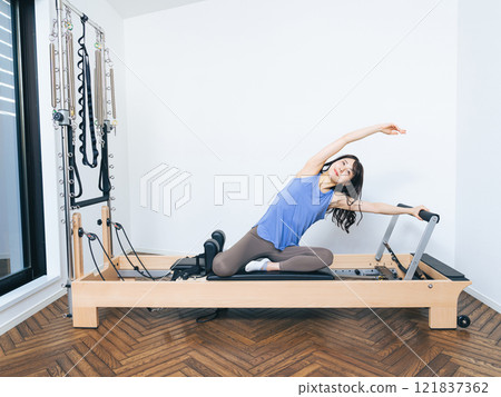 Woman doing machine pilates training Woman doing machine pilates training 121837362