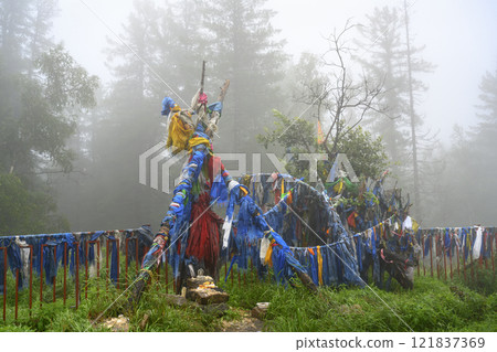 Pieces of cloth with ancient sacred texts - 'Him Morin' - symbols of Buddhism, in a foggy forest 121837369