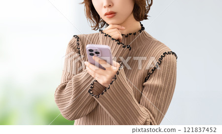 一位女商人看著她的智慧型手機並思考 一位女商人看著她的智慧型手機並思考 121837452
