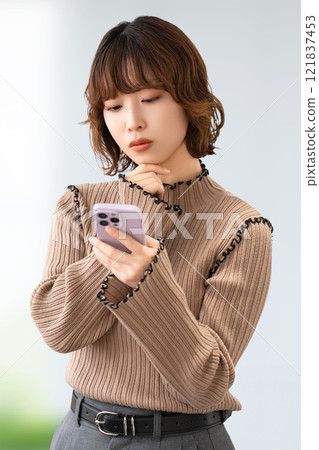 一位女商人看著她的智慧型手機並思考 121837453