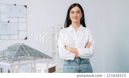 Young beautiful architect poses confidently with house model. Immaculate. Young beautiful architect poses confidently with house model. Immaculate. 121838315