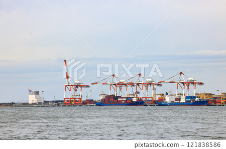Container port at Osaka Japan, container crane at Industrial port for cargo container ship. Cargo transportation and activity at modern shipping container terminal. Container port at Osaka Japan, container crane at Industrial port for cargo container ship. Cargo transportation and activity at modern shipping container terminal. 121838586