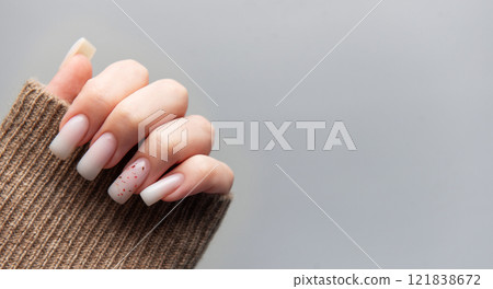 Woman showing stylish pink manicure with brown sleeve on grey background 121838672