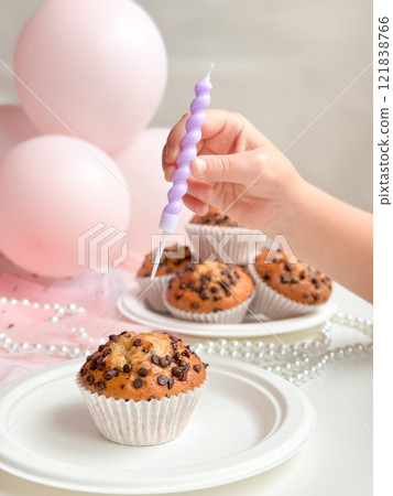 Child celebrating with chocolate chip muffins and pink balloons. Birthday concept Child celebrating with chocolate chip muffins and pink balloons. Birthday concept 121838766