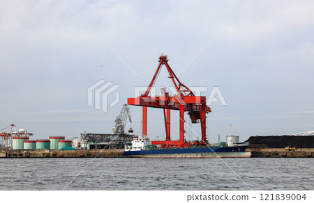 Large crane works on large coal stockpile and container crane at Industrial port for cargo container ship. Cargo transportation and activity at modern shipping container terminal. 121839004