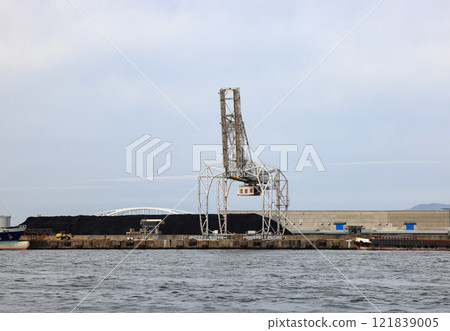 LargeLarge crane works on large coal stockpile at Osaka port. crane works on large coal stockpile at Osaka port. 121839005