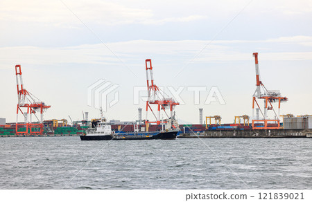 Container port at Osaka Japan, container crane at Industrial port for cargo container ship. Cargo transportation and activity at modern shipping container terminal. Container port at Osaka Japan, container crane at Industrial port for cargo container ship. Cargo transportation and activity at modern shipping container terminal. 121839021