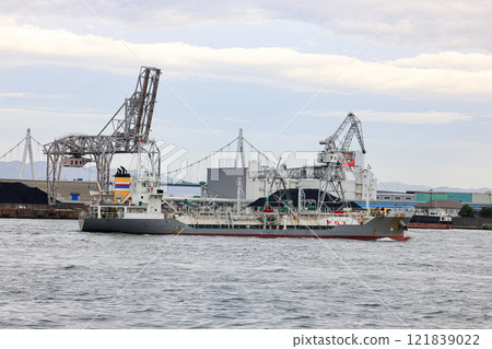 Container port at Osaka Japan, Large crane works on large coal stockpile at Osaka port. Cargo transportation and activity at modern shipping container terminal. 121839022