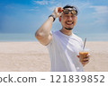 Happy man with hair bun style enjoy the iced coffee walking on the beach. 121839852