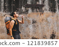 Tourist backpacker drinking bottle of water walking on the hot street in Asia. 121839857