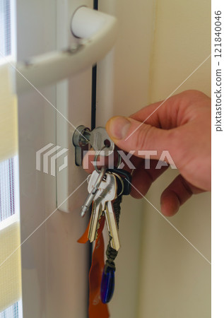 Hand Locking Door with Keys in Keyhole Close-Up. High quality photo 121840046