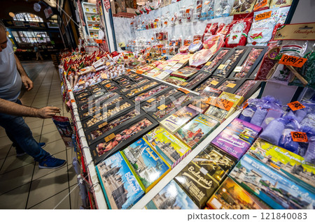Budapest, Hungary. August 29,2022. The covered market, detail of a chocolate vendor's stall. Numerous types, flavors, aromas and different packaging are on display. A customer touches the goods. Budapest, Hungary. August 29,2022. The covered market, detail of a chocolate vendor's stall. Numerous types, flavors, aromas and different packaging are on display. A customer touches the goods. 121840083