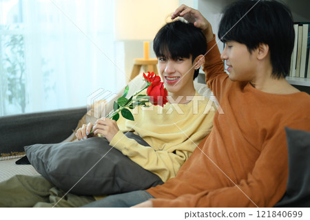 Sweet gay couple relax on the couch and sharing a romantic moment at home 121840699