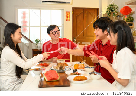 Cheerful Chinese family exchange traditional red envelopes or hongbao during a festive Chinese New Year celebration 121840823