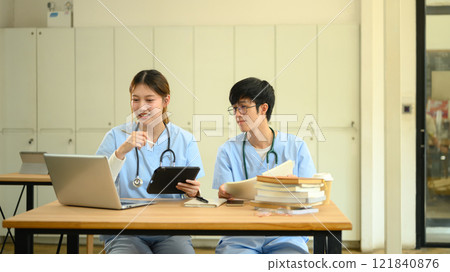Medical students in scrubs discussing and analyzing information on laptop Medical students in scrubs discussing and analyzing information on laptop 121840876