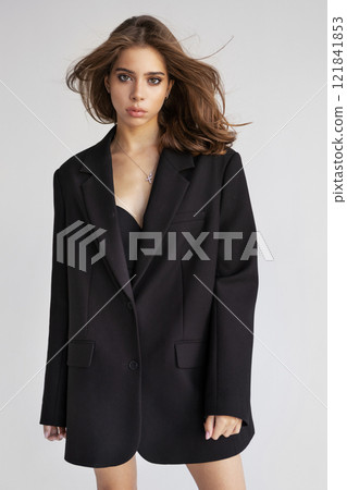 Beautiful European woman with dark hair In Oversized Black Blazer looks camera isolated on white background. Portrait Fashion model posing in studio, beauty, elegance and modern style Beautiful European woman with dark hair In Oversized Black Blazer looks camera isolated on white background. Portrait Fashion model posing in studio, beauty, elegance and modern style 121841853