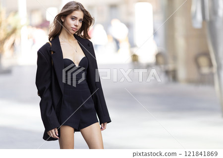 Portrait Beautiful Brunette Young Woman In Black Blazer And Mini Dress Looking At Camera, Fashion Model Outdoors On Bright Urban Background Portrait Beautiful Brunette Young Woman In Black Blazer And Mini Dress Looking At Camera, Fashion Model Outdoors On Bright Urban Background 121841869