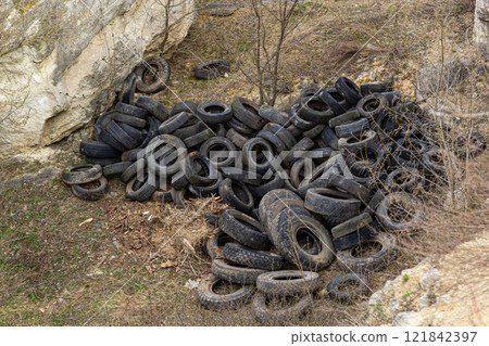 Pile of discarded tires in a natural environment near rocky terrain 121842397