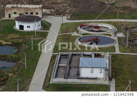 Wastewater treatment facility in a rural area showcasing circular tanks and processing buildings 121842398