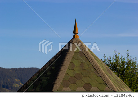 Rooftop view featuring a pointed finial against a clear blue sky and surrounding greenery Rooftop view featuring a pointed finial against a clear blue sky and surrounding greenery 121842463