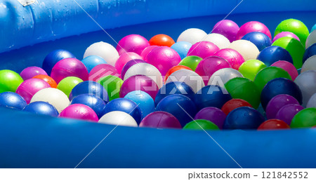 Colorful plastic balls fill an inflatable pool in a playful summer setting 121842552