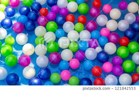 Colorful pool balls create a vibrant scene in a sunny swimming pool on a warm summer day 121842553