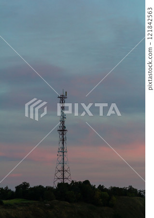 Communication tower stands against a colorful sky at dusk near a rural area Communication tower stands against a colorful sky at dusk near a rural area 121842563