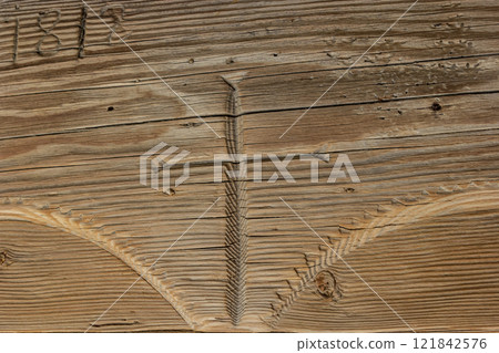 Wood carving of a simple cross found on an old wooden beam from 1815 located in a historic building 121842576