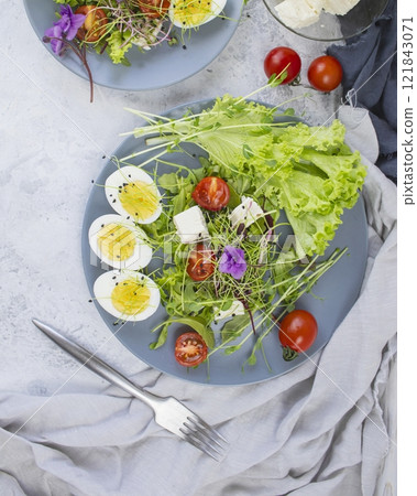 Healthy salad with lettuce, cherry tomatoes, mozzarella cheese and microgreens, on a plate, light background Healthy salad with lettuce, cherry tomatoes, mozzarella cheese and microgreens, on a plate, light background 121843071