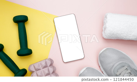 Smartphone for viewing home workouts, healthy lifestyle, sport equipment, dumbbells, foam roller for Myofascial release Smartphone for viewing home workouts, healthy lifestyle, sport equipment, dumbbells, foam roller for Myofascial release 121844450