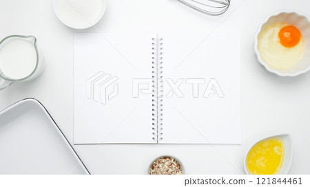 Baking ingredients for Crinkle Cake, including butter, milk, sugar, egg, nuts, open white notebook Baking ingredients for Crinkle Cake, including butter, milk, sugar, egg, nuts, open white notebook 121844461