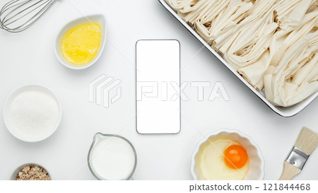 For baking Crinkle Cake. Mockup design for recipe or food blog. Cooking ingredients and smartphone with blank screen 121844468