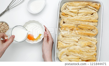 Baked Crinkle Cake, phyllo dough, mixing egg and sugar to make custard 121844471