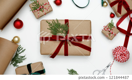 Creating a festive, natural holiday scene, wrapped Christmas gifts with green thuja branches Creating a festive, natural holiday scene, wrapped Christmas gifts with green thuja branches 121844487
