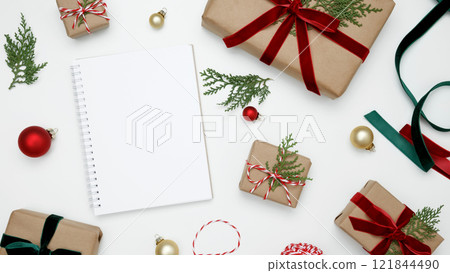 Wrapped Christmas gifts and thuja branches in a festive setup, mockup of white notebook Wrapped Christmas gifts and thuja branches in a festive setup, mockup of white notebook 121844490