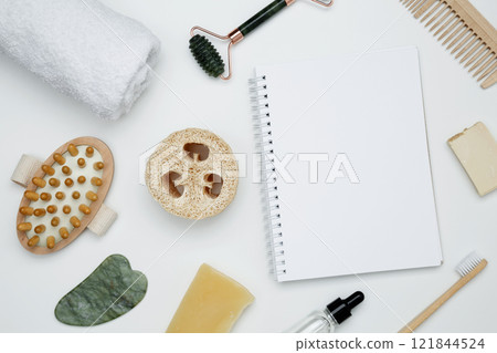 Eco-friendly beauty products: massage brush, loofah, marble roller, towel, reusable cotton pads, mock up white notebook, sustainable self-care concept 121844524