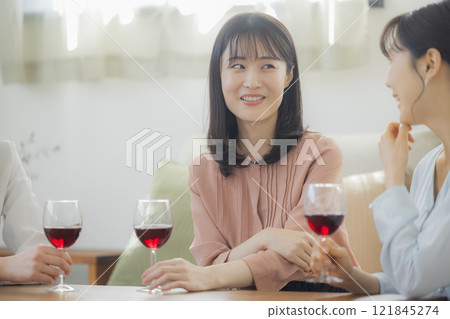 Woman holding a glass of alcohol in the living room Woman holding a glass of alcohol in the living room 121845274