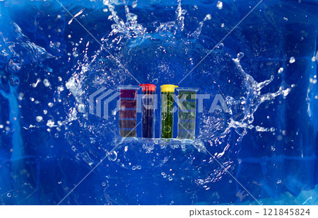 PH acid level test kit on quality water on purple yellow. PH acid level tester kit fall on water splashing splattering over blue background, top angle 121845824