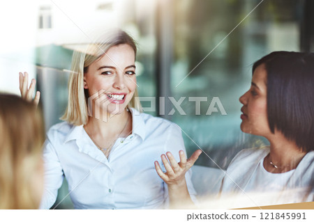 Female office worker on a break with colleagues talking and having a conversation at work. Business people spending time together inside. Smiling corporate business woman with team indoors 121845991