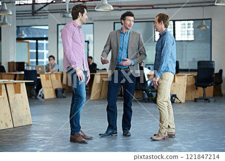 Group or team of business colleagues and coworkers talking, discussing and planning in a modern office. Corporate and professional men sharing ideas, information and strategy while standing at work 121847214
