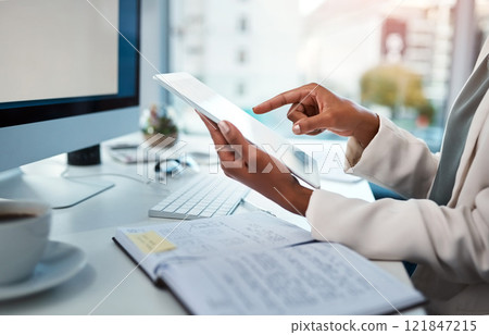 Businessperson hands working on a digital tablet at a desk in a modern office. Closeup of business professional multitasking documents or checking data, schedule and daily plan at the workplace. 121847215